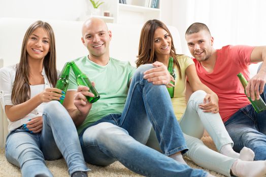 Four friends enjoying with beer together at the home party.