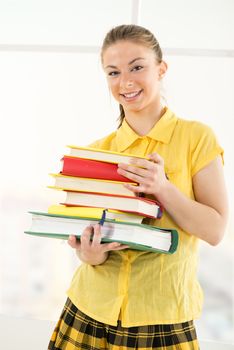 Happy beautiful female student standing with Colorful books