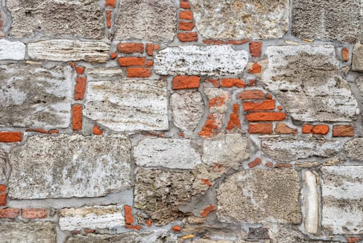 Broken old bricklaying wall fragment from red white bricks and damaged plaster background texture.