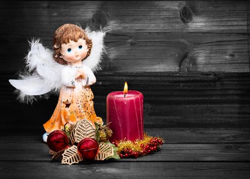 Christmas greeting card with candle and angels on wooden background black and white.