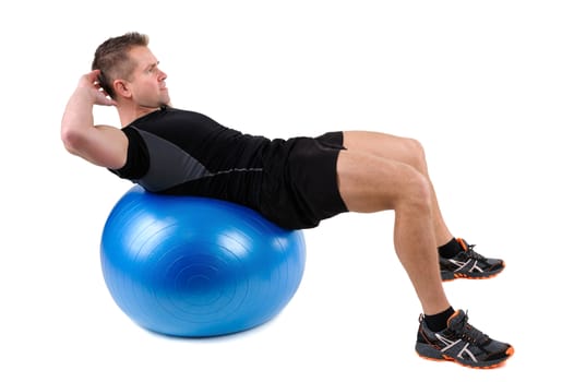 Young man shows finishing position of Abdominal Fitball Workout, isolated on white