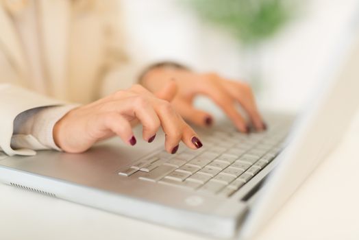 Close-up of female hand with painted nails on the keyboard of the laptop.
