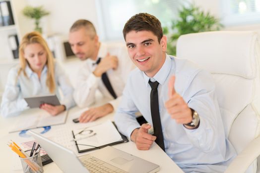 Business people having a meeting. Focus is on happiness young businessman with thumb up and looking at camera. Selective focus.