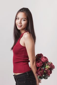 closeup fashion portrait of asian young sexy woman posing in studio with red rose flower.