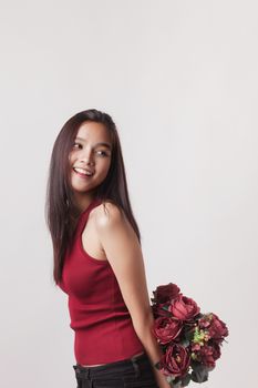 closeup fashion portrait of asian young sexy woman posing in studio with red rose flower.