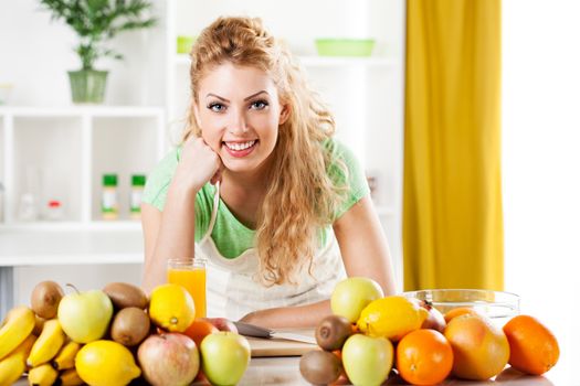 Beautiful young woman in a kitchen with fruits. Looking at camera.