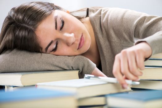 Tired student fell a sleep between many books, while learning.