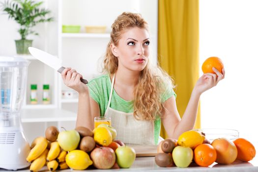 Beautiful young woman in a kitchen with fruits and knife. Looking at camera.