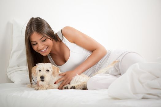Young beautiful woman and her dog resting in bed
