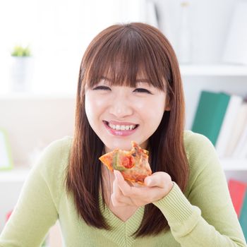 Asian female eating pizza at home. Woman living lifestyle indoors.
