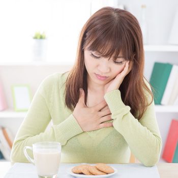 Portrait of Asian girl no appetite while having breakfast, milk and cookies on dining table. Young woman indoors living lifestyle at home.