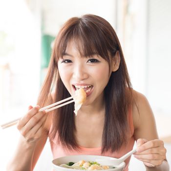 Asian girl eating delicious dumplings at Chinese restaurant. Young woman living lifestyle.