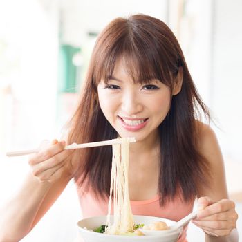 Asian girl eating noodles at restaurant. Young woman living lifestyle.