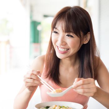 Asian girl eating dumpling noodles and talking with friend at Chinese restaurant. Young woman living lifestyle.