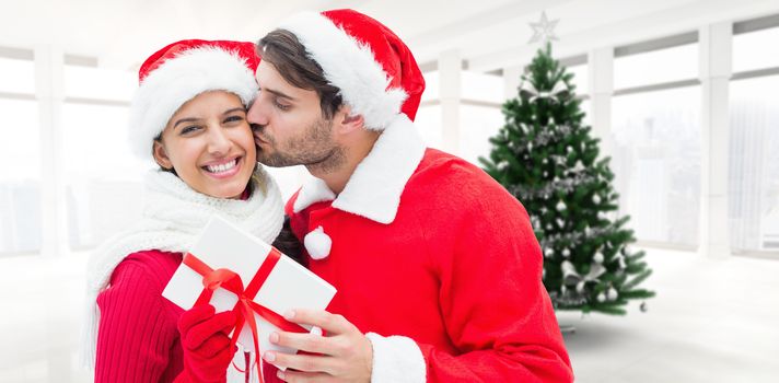 Festive young couple holding gift against home with christmas tree