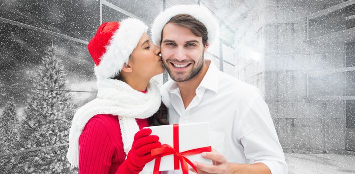 Festive young couple holding gift against window overlooking snowy forest