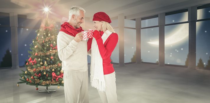 Happy winter couple with mugs against home with christmas tree