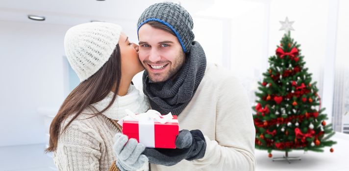 Winter couple holding gift against home with christmas tree