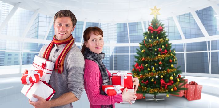 Couple holding lots of presents against home with christmas tree