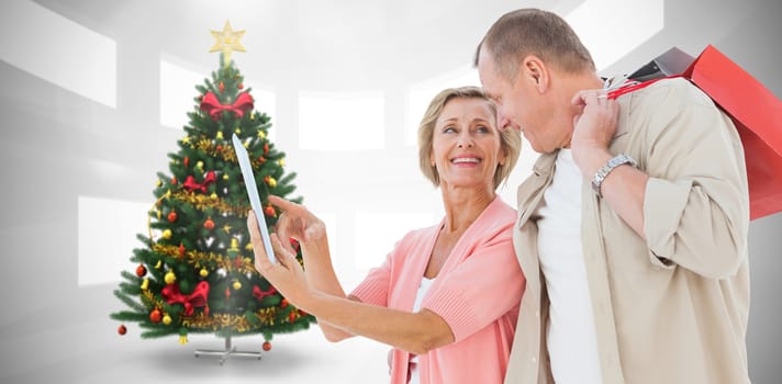 Couple with shopping bags and tablet against home with christmas tree