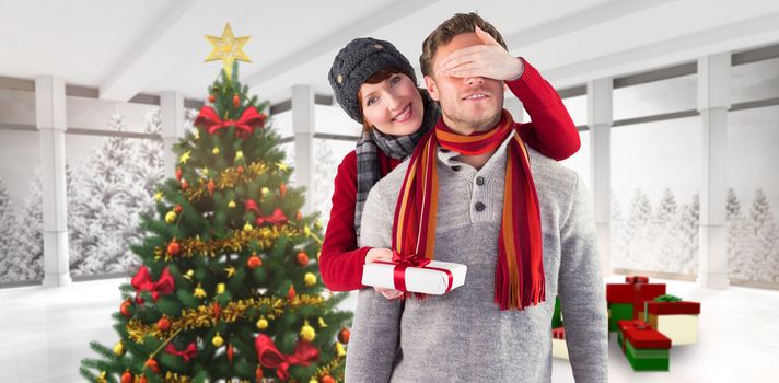 Woman giving man a present against home with christmas tree