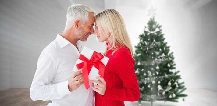 Loving couple with gift against home with christmas tree