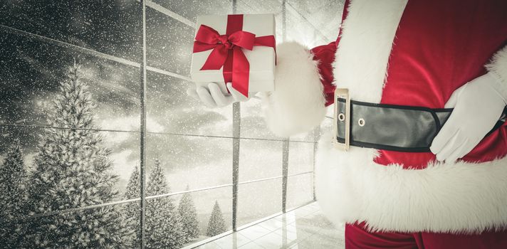 Mid section of santa holding gift against window overlooking snowy forest