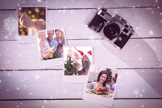 Happy father helping his son to put an angel on the Christmas tree against instant photos on wooden floor