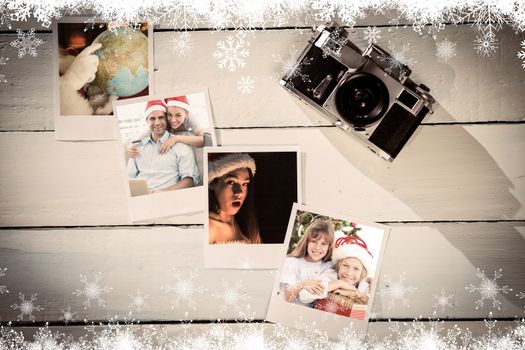 Happy couple in santa hats shopping online with laptop against instant photos on wooden floor