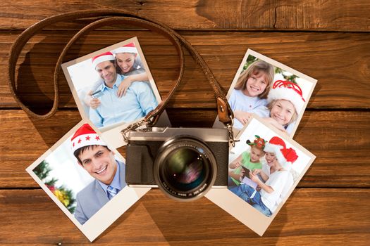 Cute couple in santa hats shopping online with laptop against instant photos on wooden floor