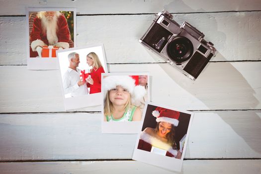 Smiling couple embracing and holding gift against instant photos on wooden floor