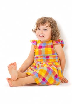 Cute little girl sitting on the floor and smiling on white background.