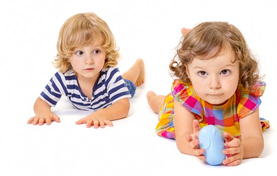 Funny boy and girl are lying together isolated on white background. Focus on little boy.