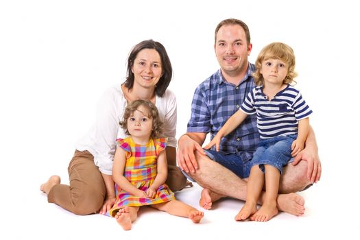 Happy family of four smiling while standing against white background.