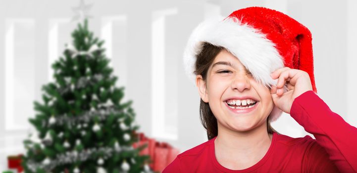 Festive little girl smiling at camera against home with christmas tree