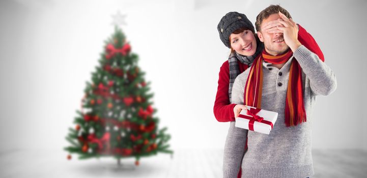 Woman giving man a present against home with christmas tree