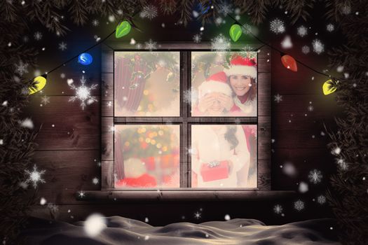 Mother and daughter with gift against christmas home seen through frosty window