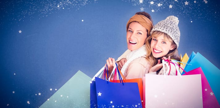 Beautiful women holding shopping bags looking at camera  against blue background