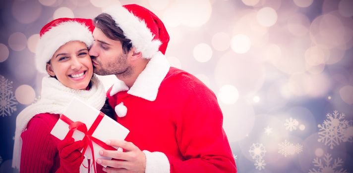 Festive young couple holding gift against glowing christmas background