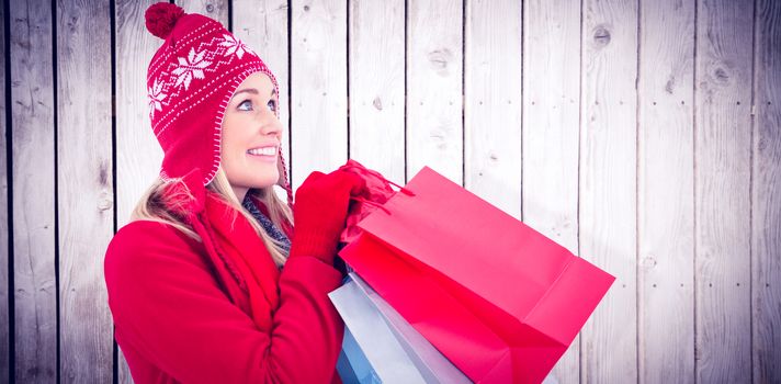 Blonde in winter clothes holding shopping bags against wooden planks