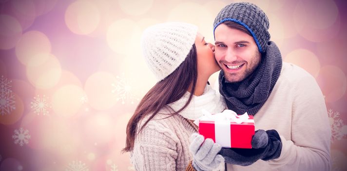 Winter couple holding gift against glowing christmas background