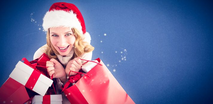 Girl in winter fashion holding presents and shopping bags against blue background