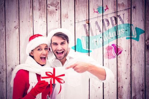 Festive young couple holding gift against wooden planks