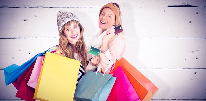 Beautiful women holding shopping bags looking at camera  against white wood
