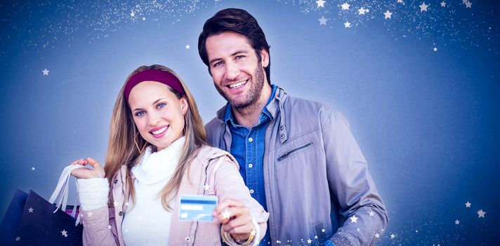 Smiling couple with shopping bags showing credit card against blue background