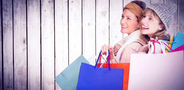 Beautiful women holding shopping bags looking away  against wooden planks