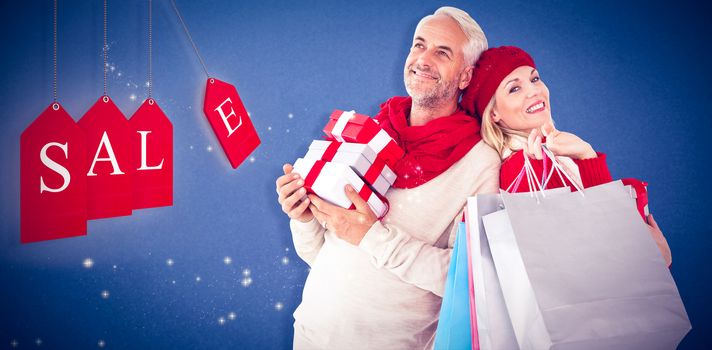 Happy festive couple with gifts and bags against blue background