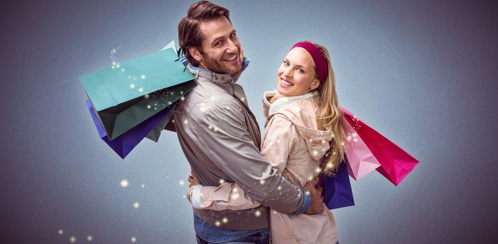 Smiling couple with shopping bags embracing against blue background