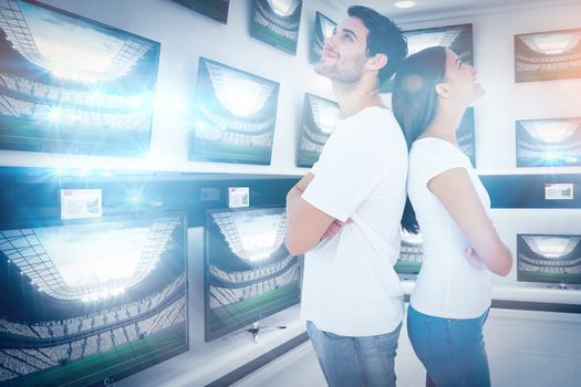 Happy couple standing looking up against televisions for sale