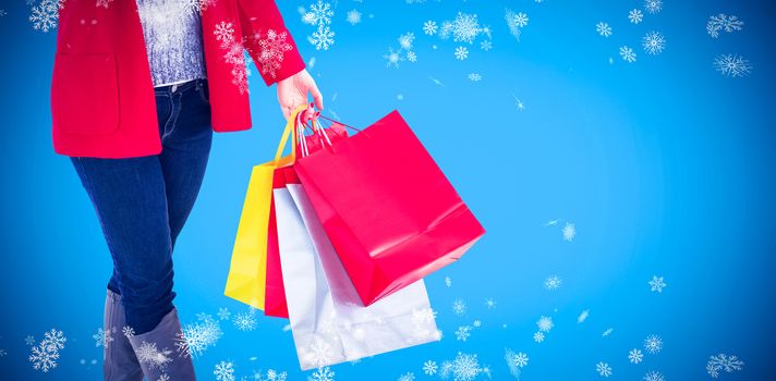 Happy blonde in winter clothes holding shopping bags against blue background with vignette